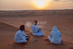 Ilustrační obrázek k zájezdu Omán (prosinec 2018), kde sedí beduíni na písečné duně v poušti.